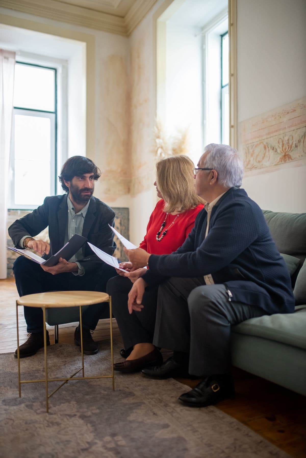 An advisor discussing documents with a couple in a cozy room.